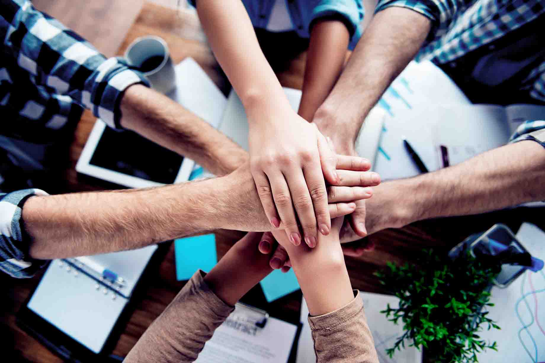 Hands stacking on one another in a show of collaboration/team work, in the workplace, showing a good Workplace Culture